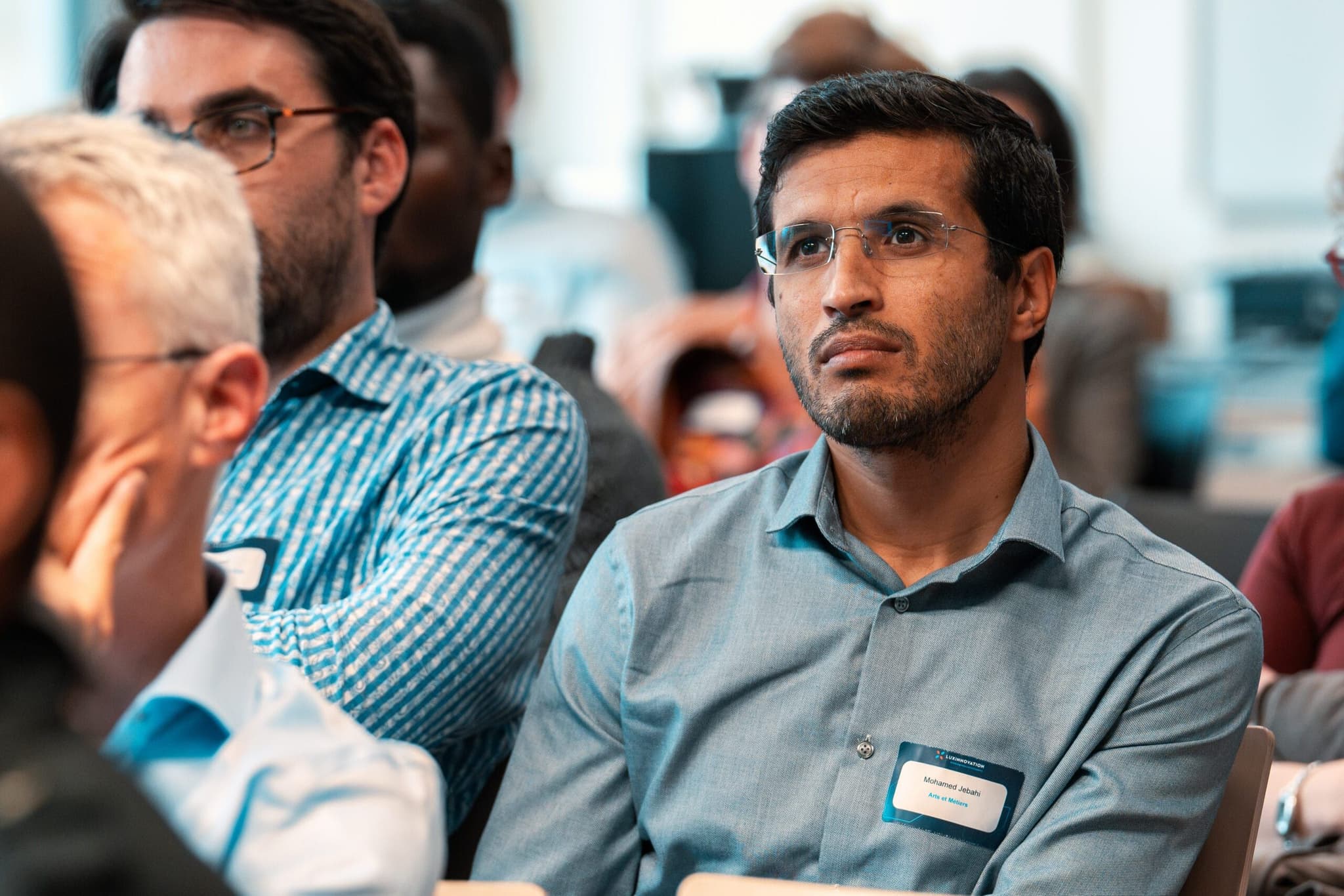 Event photographer Luxembourg: conference attendee listening with name badge