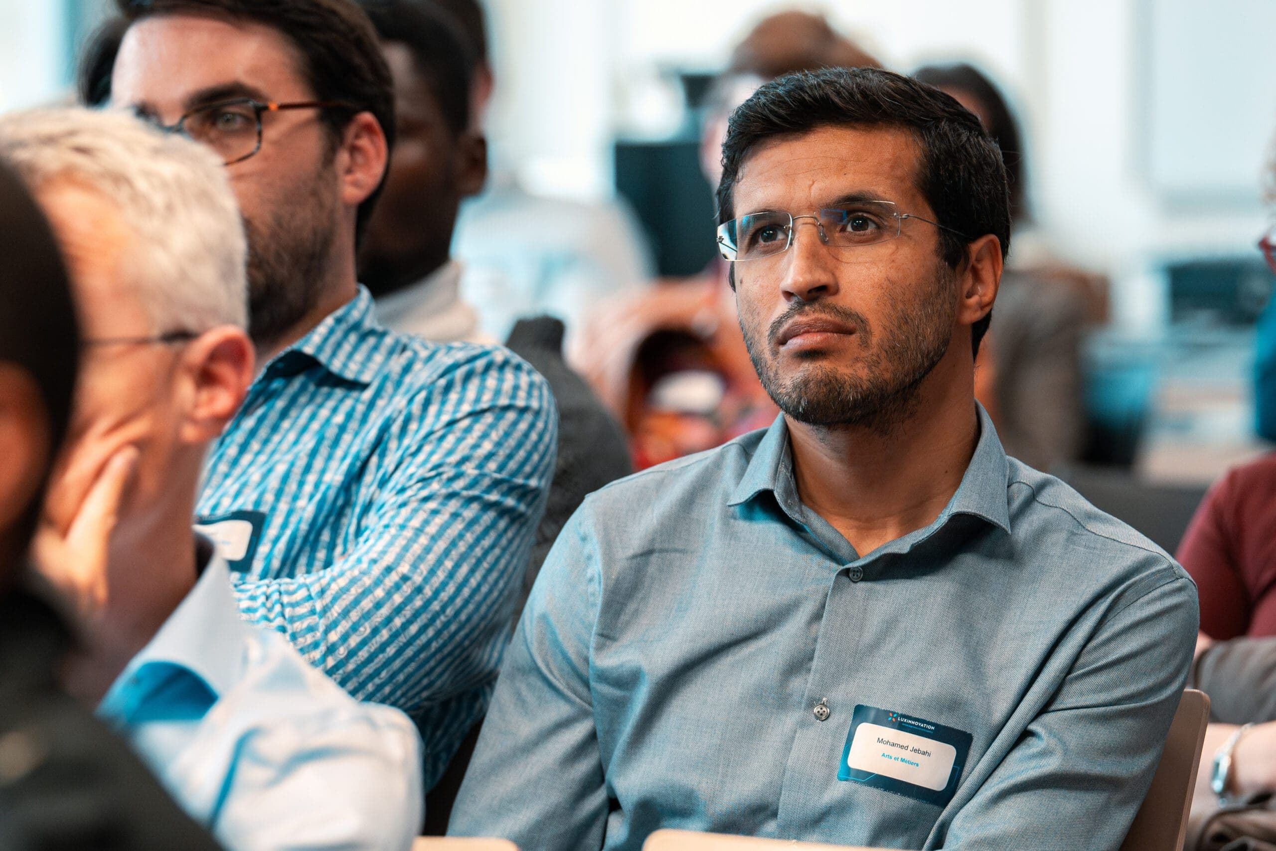Event photographer Luxembourg: conference attendee listening with name badge